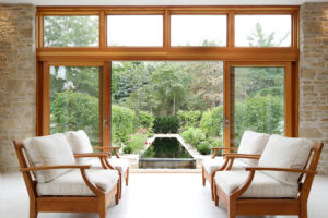 Four plush lounge chairs in front of large sliding glass doors that lead out to a garden