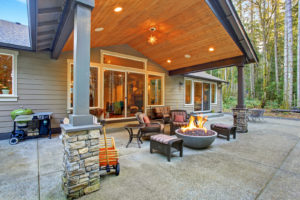 Large back yard with grass and covered patio with firepit.