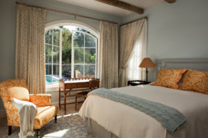 A bedroom featuring arched windows opening out to the backyard