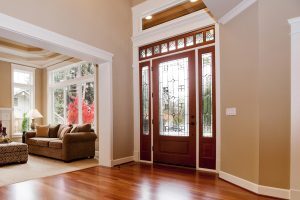 Interior entry way of a home with a wooden front entry door that has glass inserts